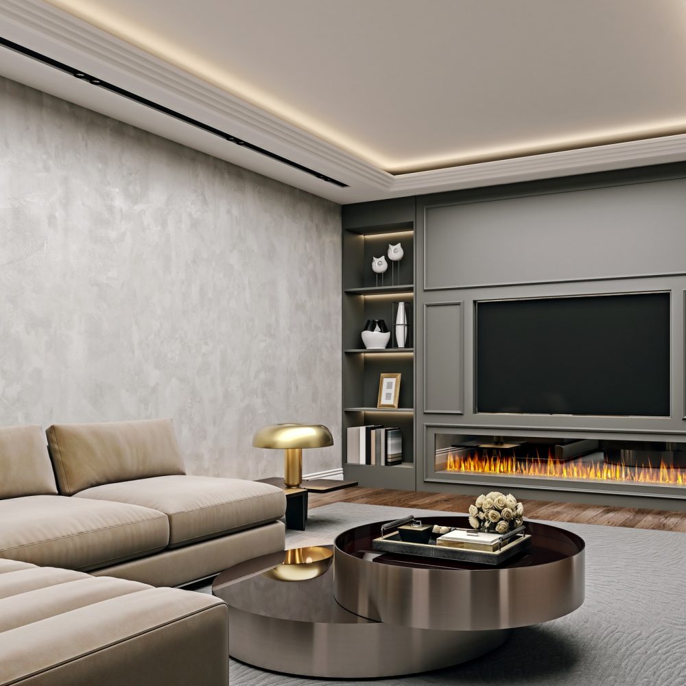 A modern living room with a beige sectional sofa, round coffee tables, a built-in fireplace under a large TV, and shelves with decor items. The room features soft lighting and a contemporary design.