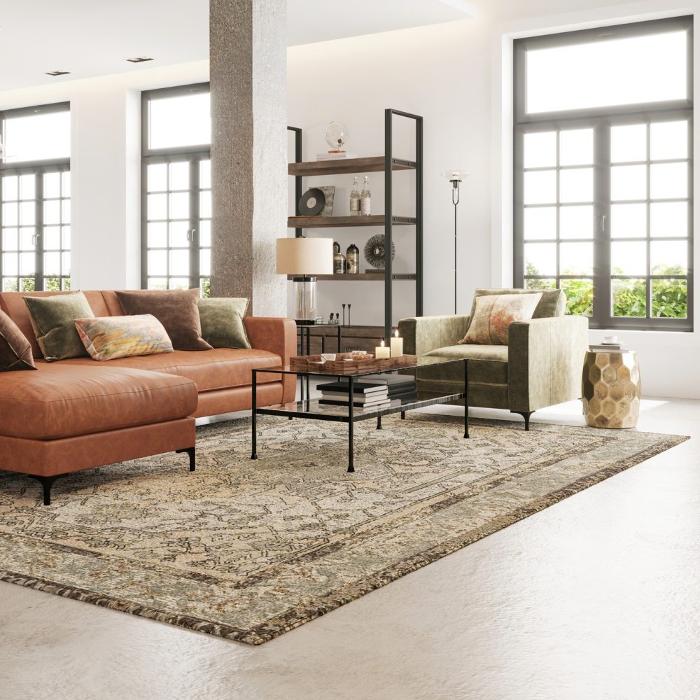 Modern living room with large windows, a brown leather sectional sofa, a green armchair, a patterned rug, a bookshelf, and neutral decor in a bright, airy space.